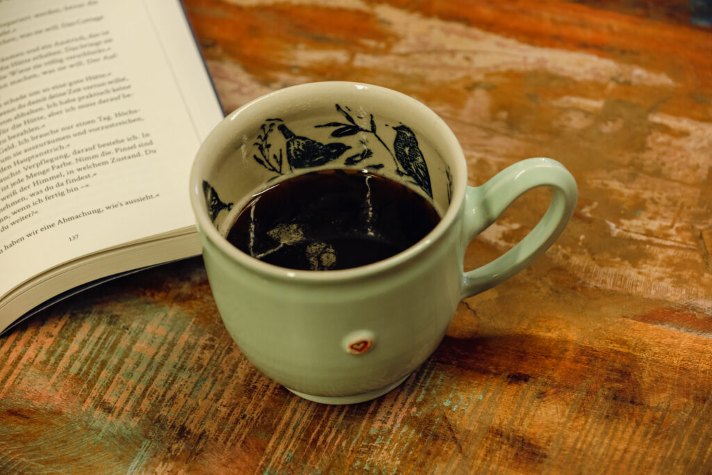 Die Handgemachte tasse mit Kaffee steht auf einem Holztisch.